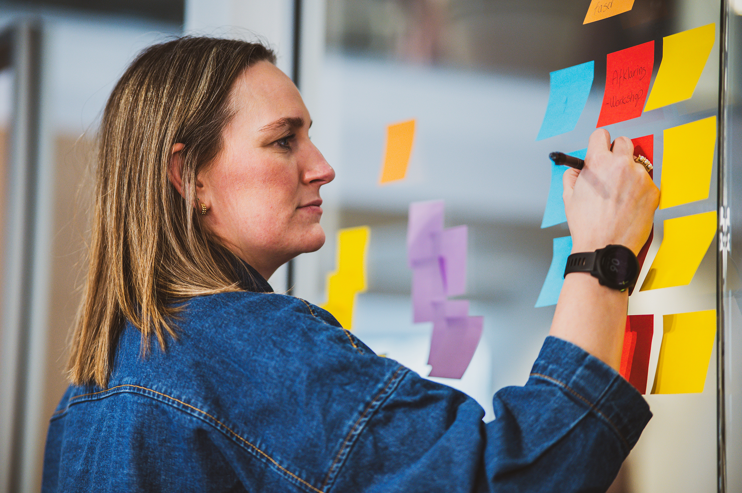Lait projektleder Sara skriver noter på post its