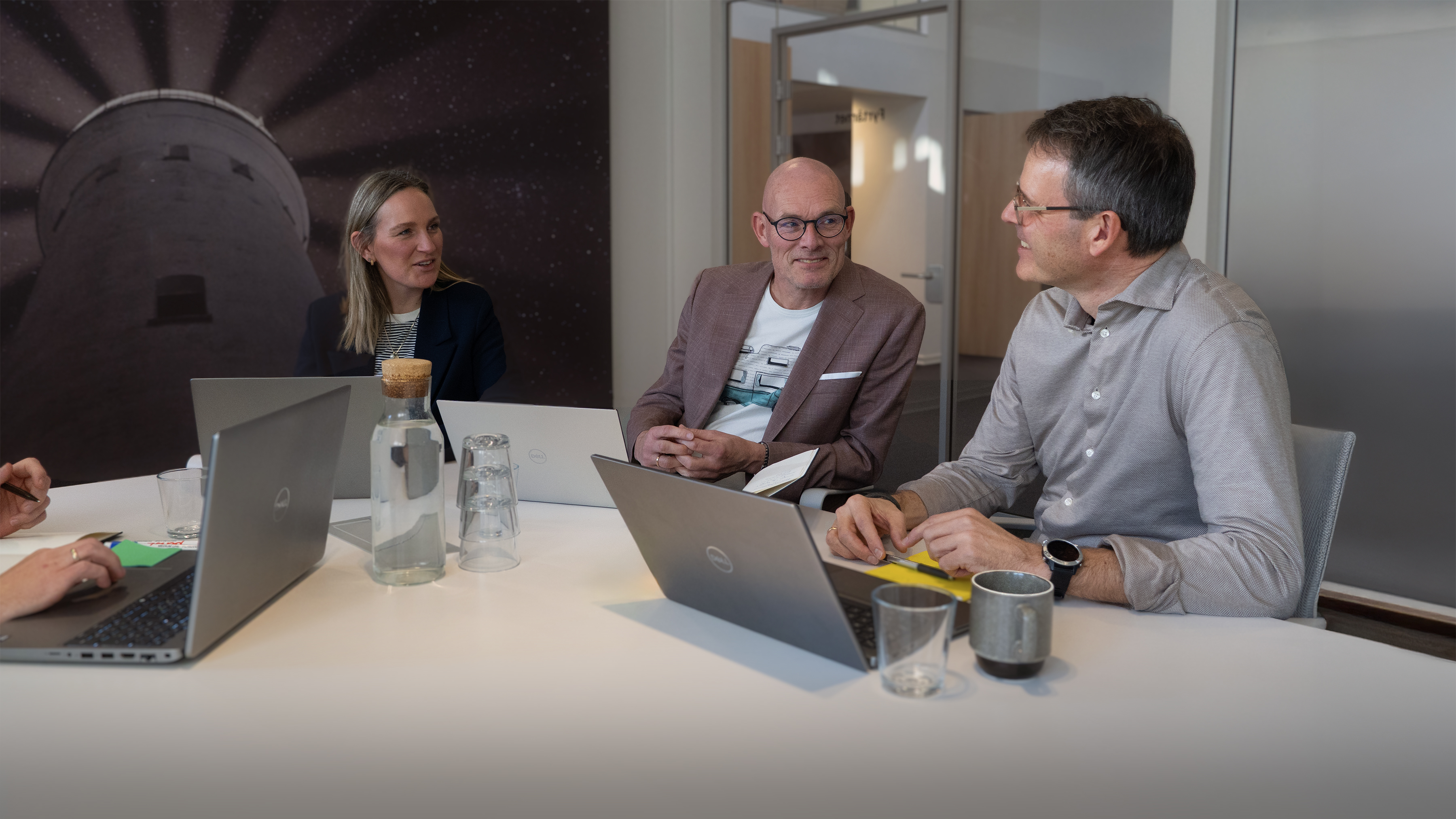 Tre medarbejdere fra lait sidder en samtale om et mødebord